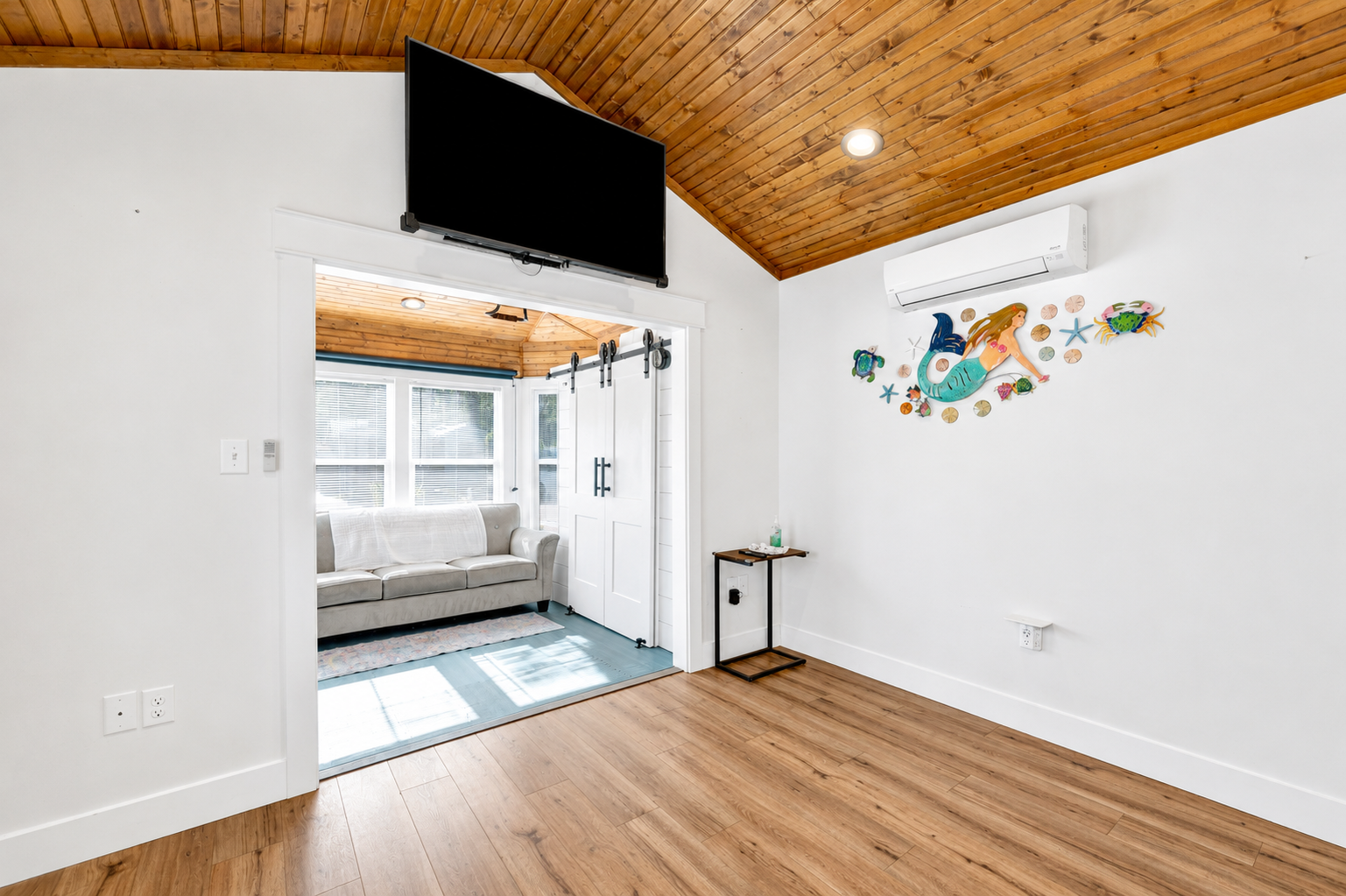 Coach house interior with wood ceiling, barn door and mermaid wall art at Terry Cove Lot 2A